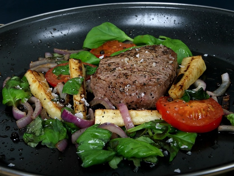 beef, spinach, and tomato cooking in a fry pan