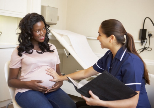 Pregnant woman meeting with nurse for checkup in physician's office