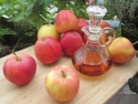 apples and bottle of vinegar on table in garden
