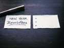 Paper next to pen on table says "New Year Resolutions." 