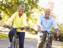 Two senior citizens ride bikes on a sunny day