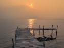 wooden dock extending into a lake with a sunset obscured by heavy smoke from a wildfire