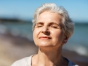 Woman with short gray hair with face lifted to the sun